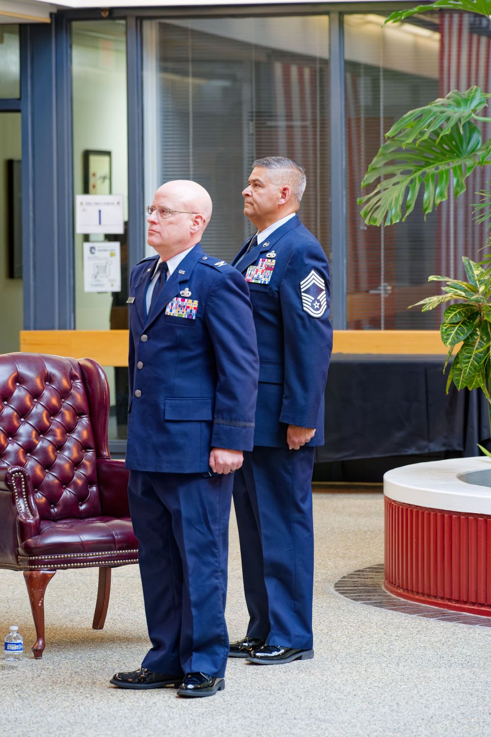 Two US Air Force officers in dress blue uniforms standing at attention during a military ceremony.