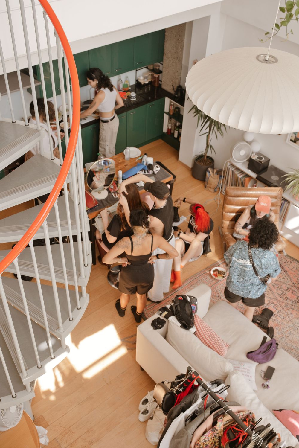 Aerial view of a lively indoor gathering with people socializing in a stylish loft space with spiral staircase.