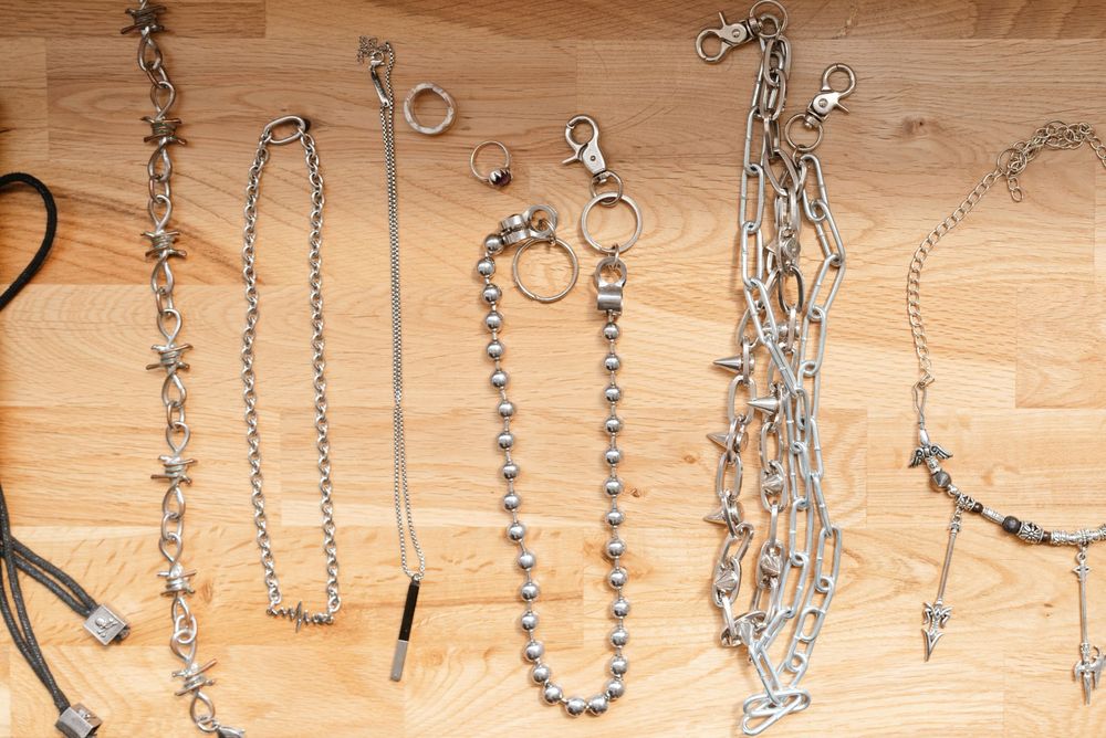 Collection of silver metal chain necklaces and bracelets with cross charms laid flat on a wooden surface.