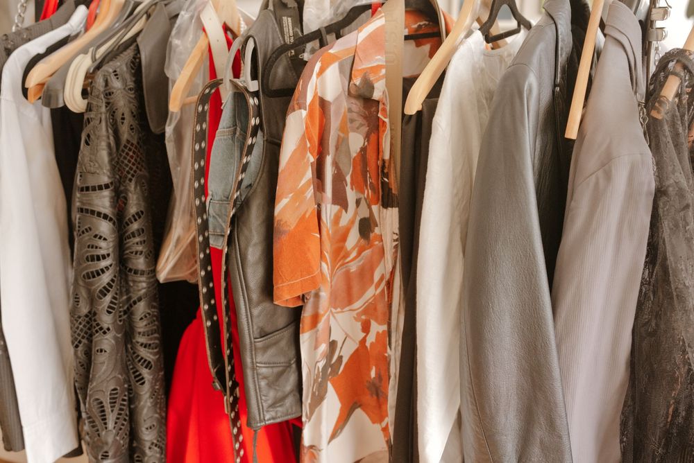 A colorful collection of women's clothing hanging on a rack, featuring orange, gray, and red garments in a boutique.