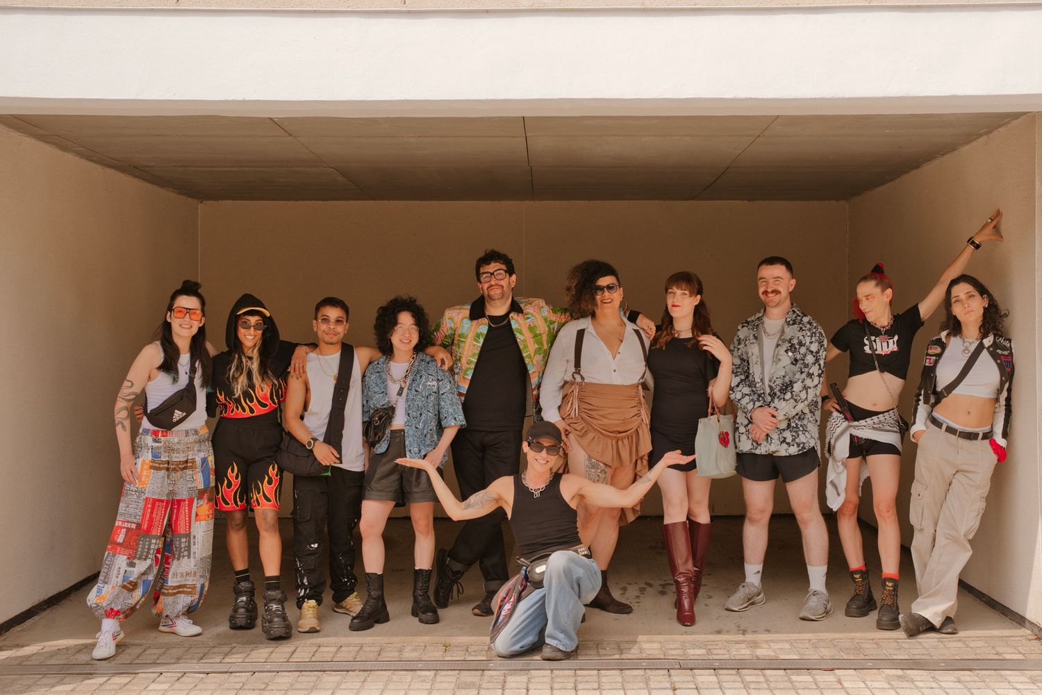 A diverse group of friends posing together in a tunnel, wearing colorful festival outfits and costumes.