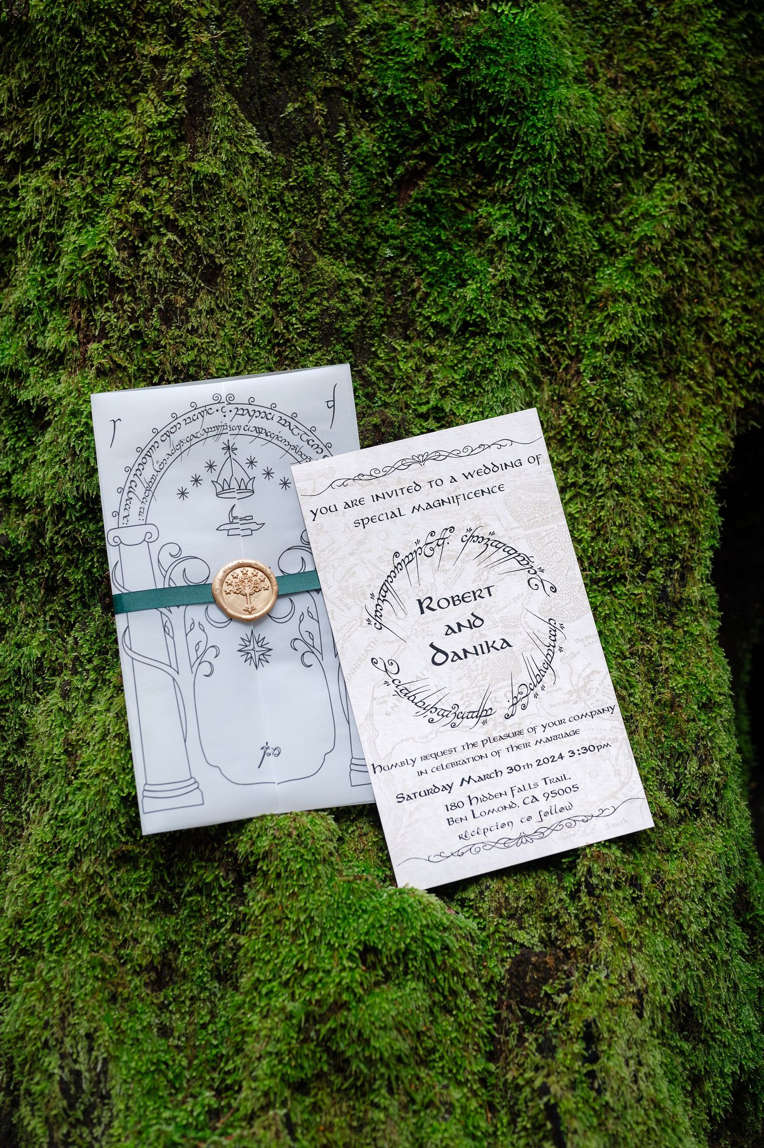 Lord of the Rings themed wedding invitations for Robert and Danika displayed on moss-covered bark.