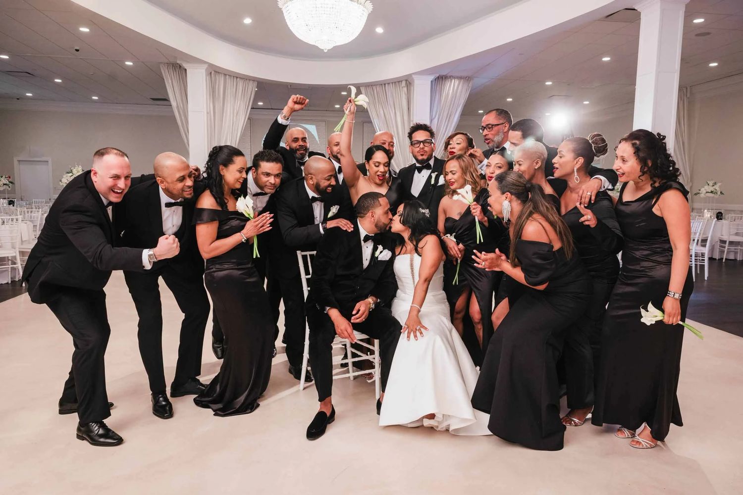 Dramatic Portrait of entire wedding party as well as the bride and groom at an elegant wedding venue. The couple kisses passionately.