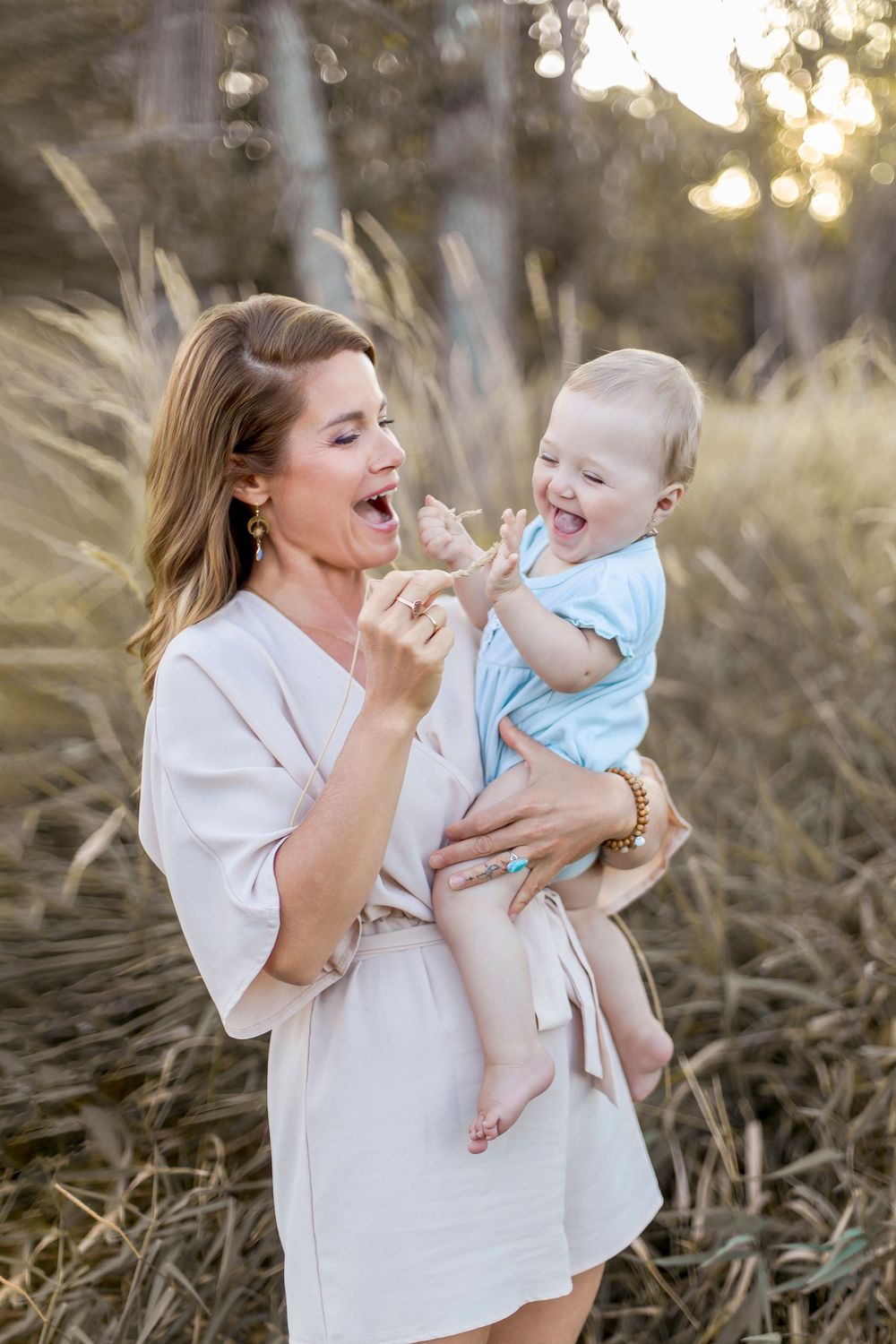 A tender moment captured between parent and child playing together outdoors at sunset in a grassy field.