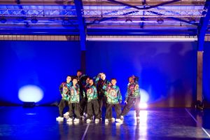 Young dancers performing a group routine under dramatic blue stage lighting.