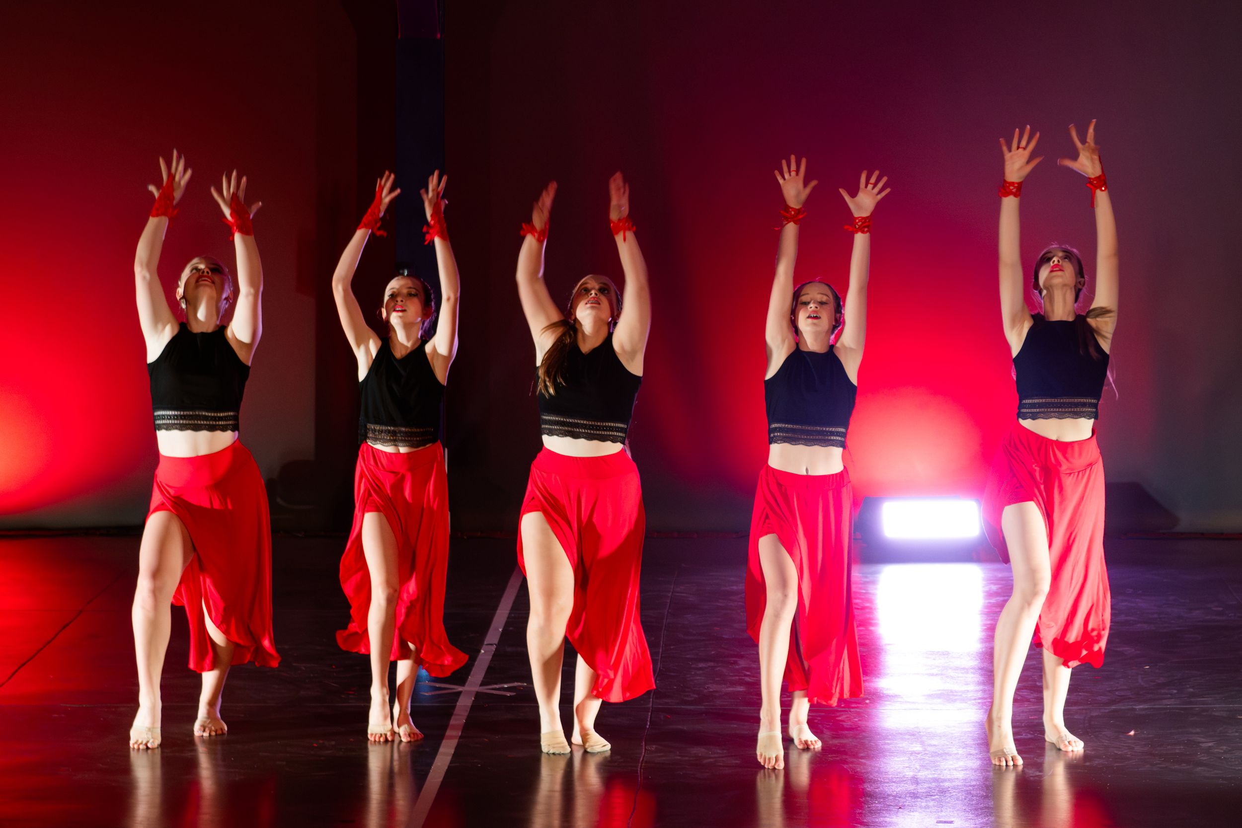 Dancers performing in formation during a live stage show photographed by Rynali Photography.