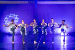 Group of dancers performing under vibrant stage lighting at a dance concert.