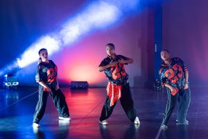 A picture showing energetic dance performance captured under dramatic blue and red stage lighting.