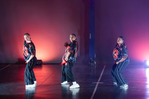 Energetic dance performance photographed under dramatic stage lighting.