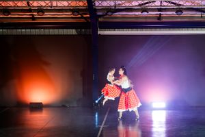 Dance duo performing together under colourful theatrical lighting during a live show.