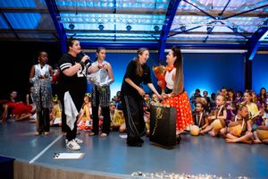 Dance performers and cast celebrating together on stage at the end of a live production.