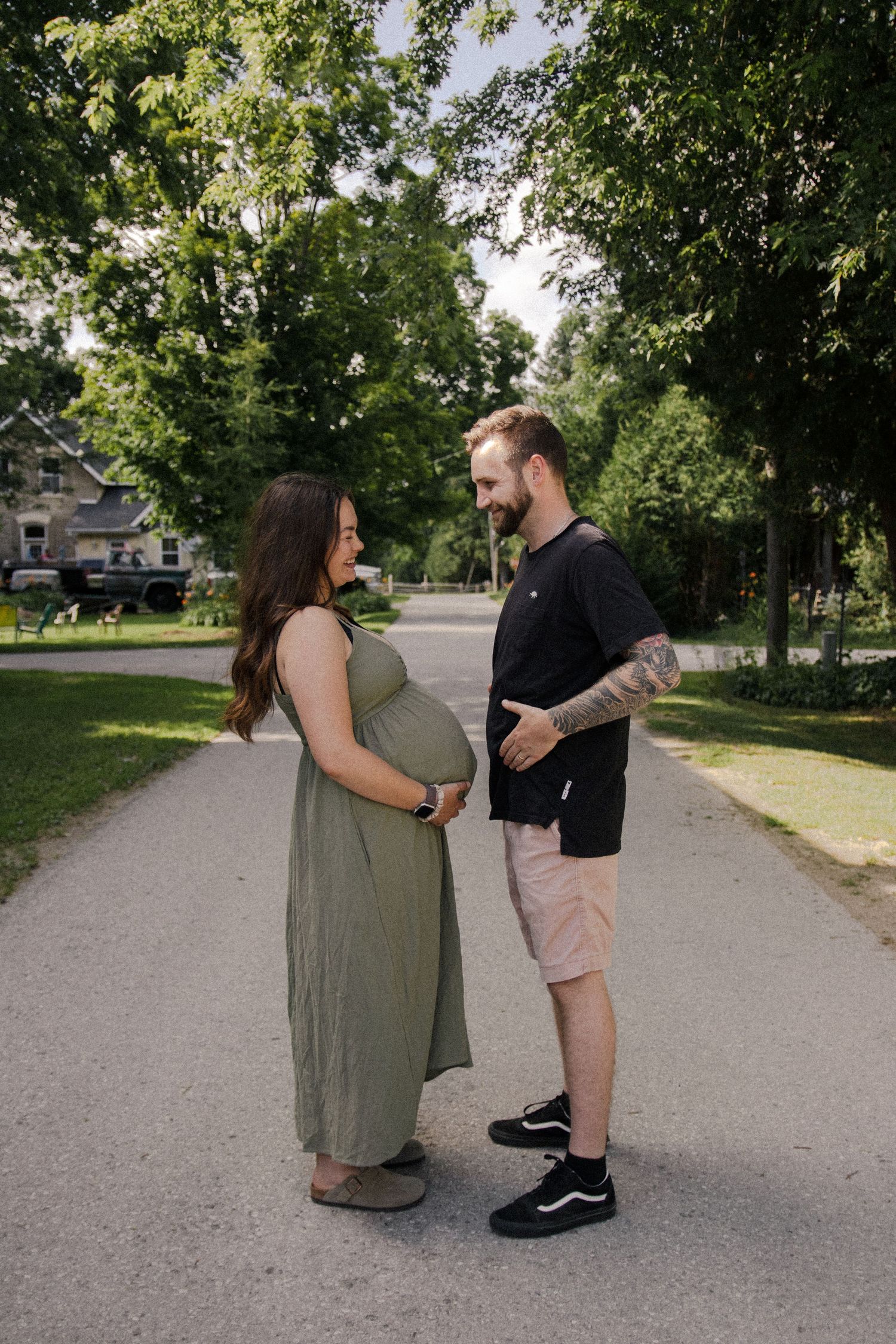 a husband and wife laughing in the street during their maternity photoshoot