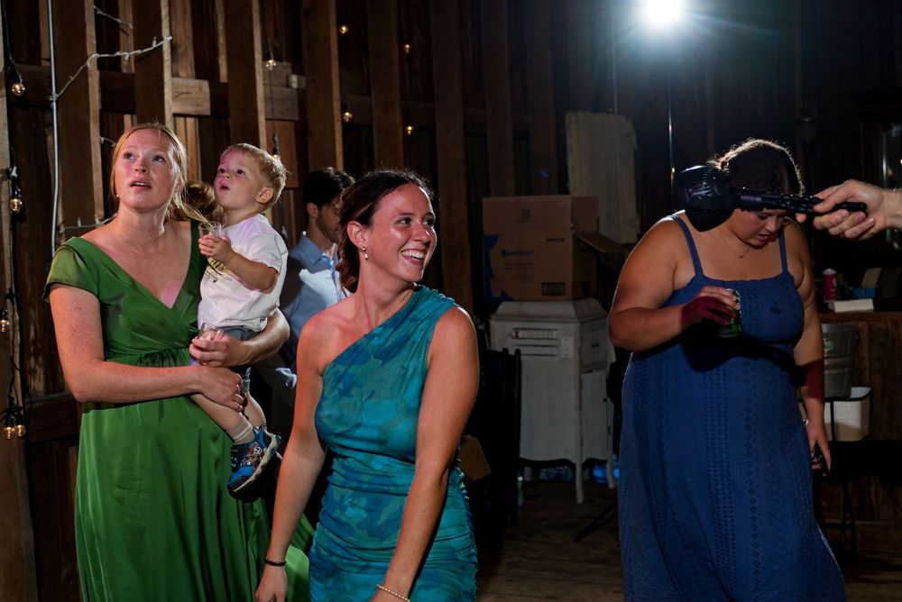A smiling guest being cooled by a hand-held fan on the dance floor at a wedding reception.