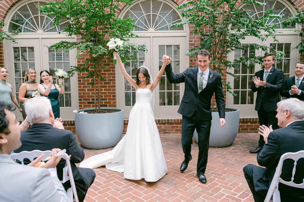 Newlyweds celebrate joyfully as they walk back down the aisle after their outdoor wedding ceremony.