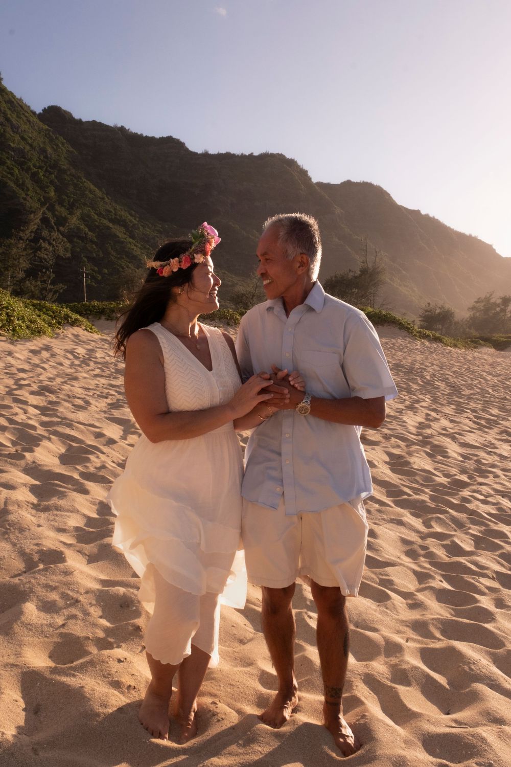 Couple holding hands on a secluded North Shore Oahu beach framed by lush Hawaiian mountains during a North Shore Oahu photography session