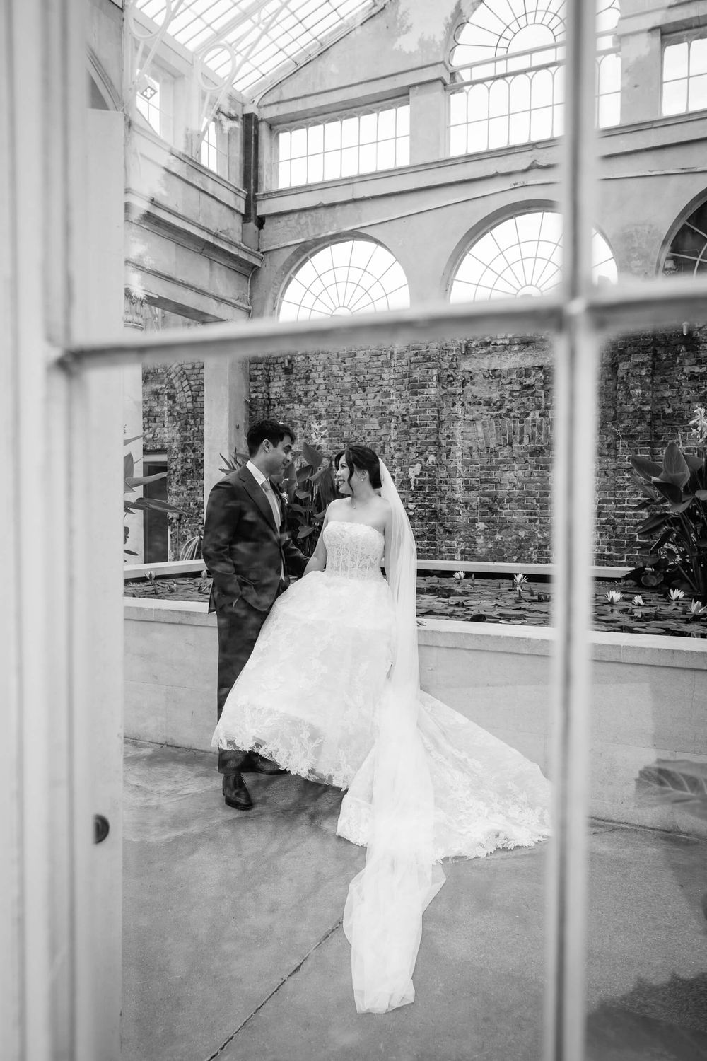 bride and groom through the window at the great conservatory