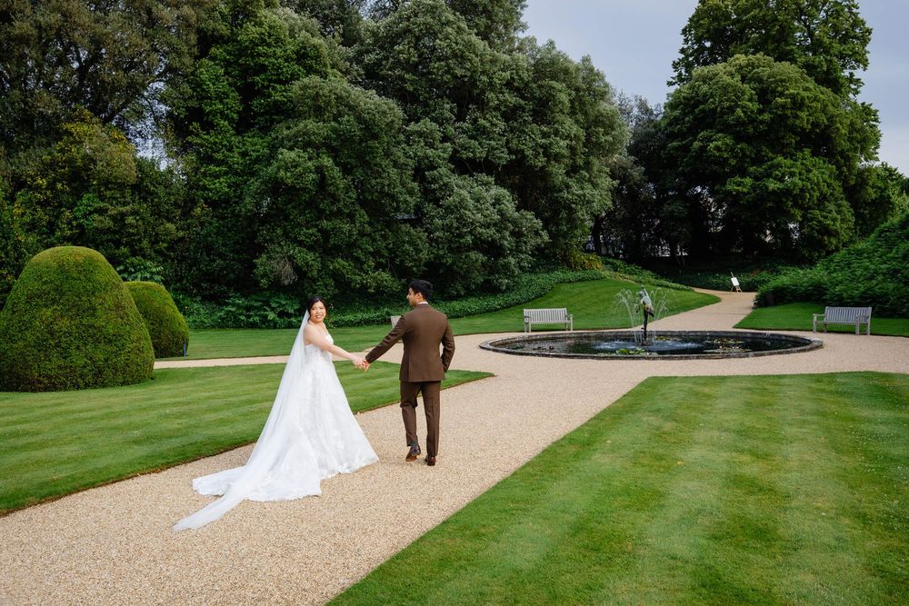 photo of the bride and groom walking through the wedding venue grounds