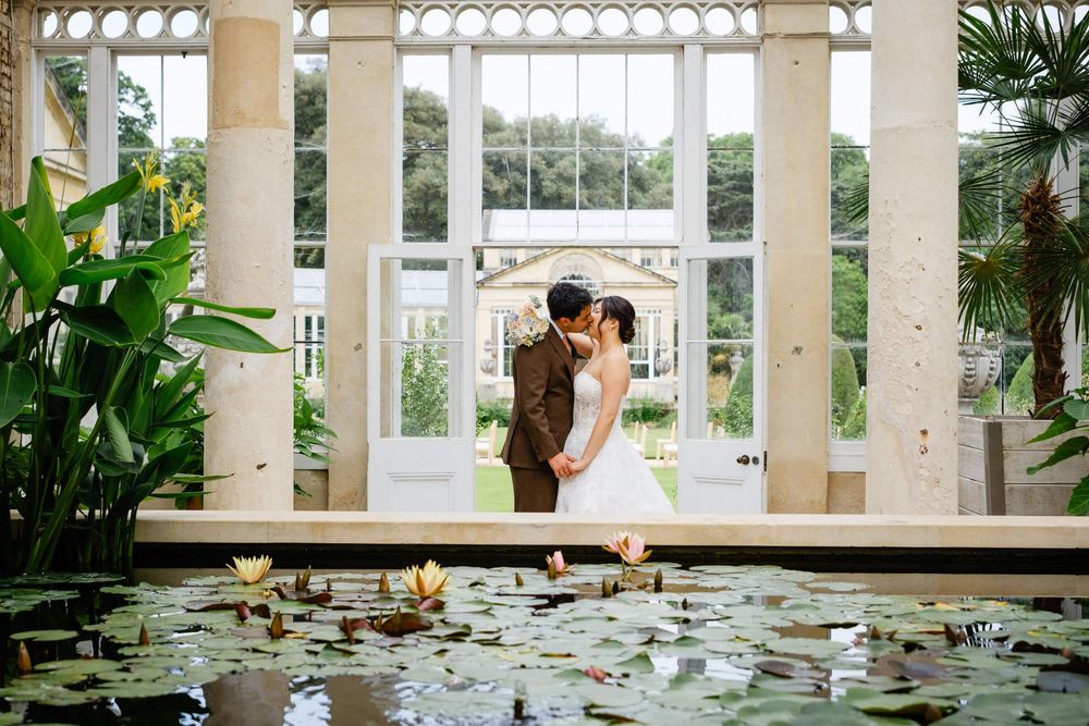 Bride and groom kiss in the great conservatory at Syon Park London