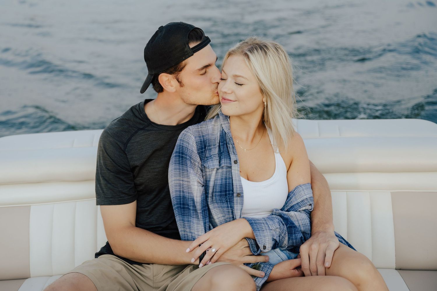 newly engaged couple snuggles during a relaxed boat ride on lake wissota in chippewa falls, WI.