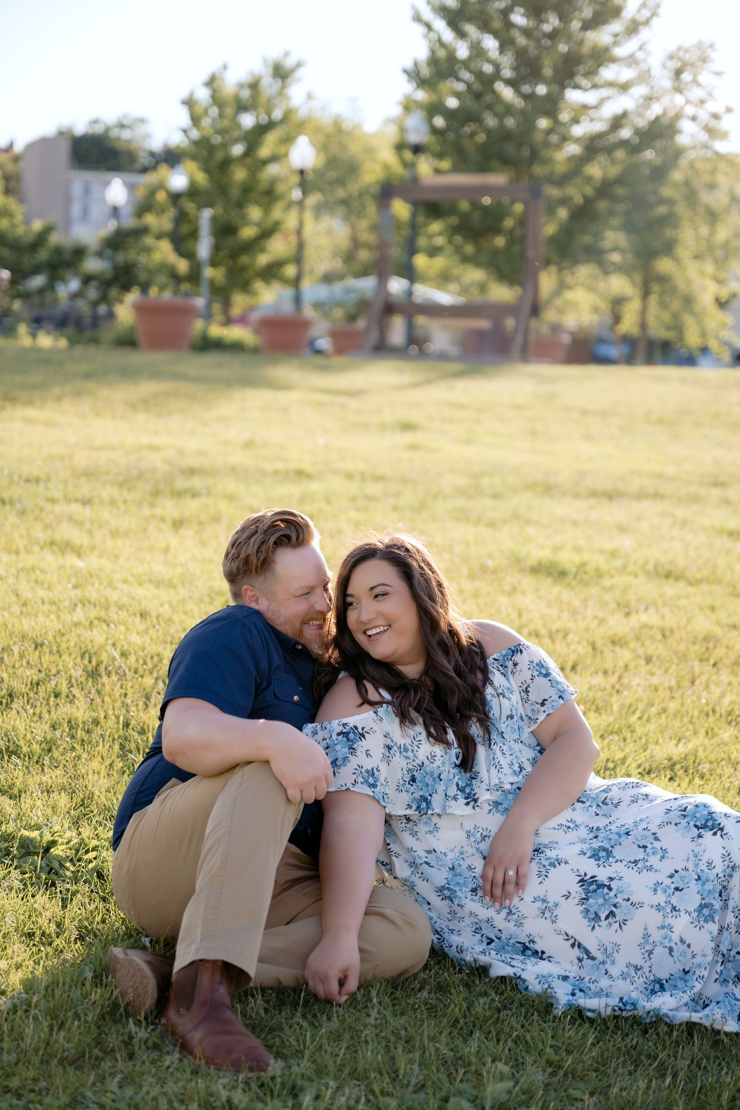 Engaged couple lounges in the waterfront park during their outdoor Spring engagement session in Stillwater, MN.