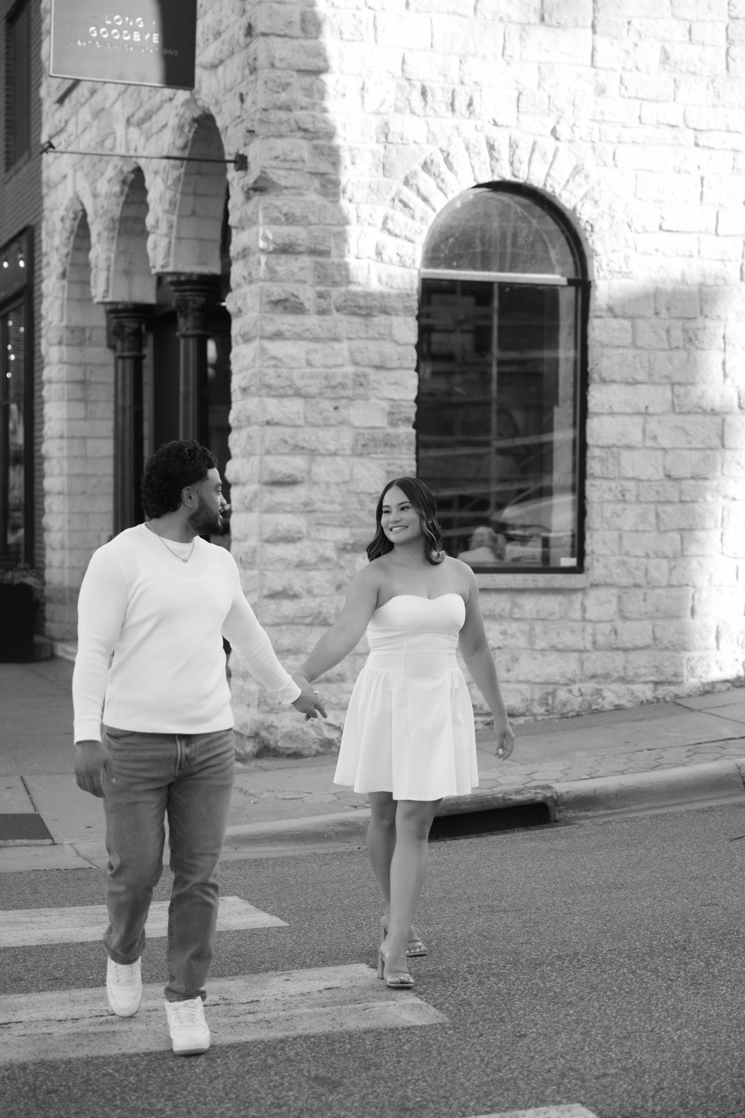 Engaged couple walks hand in hand in historic downtown Stillwater for their engagement photos.