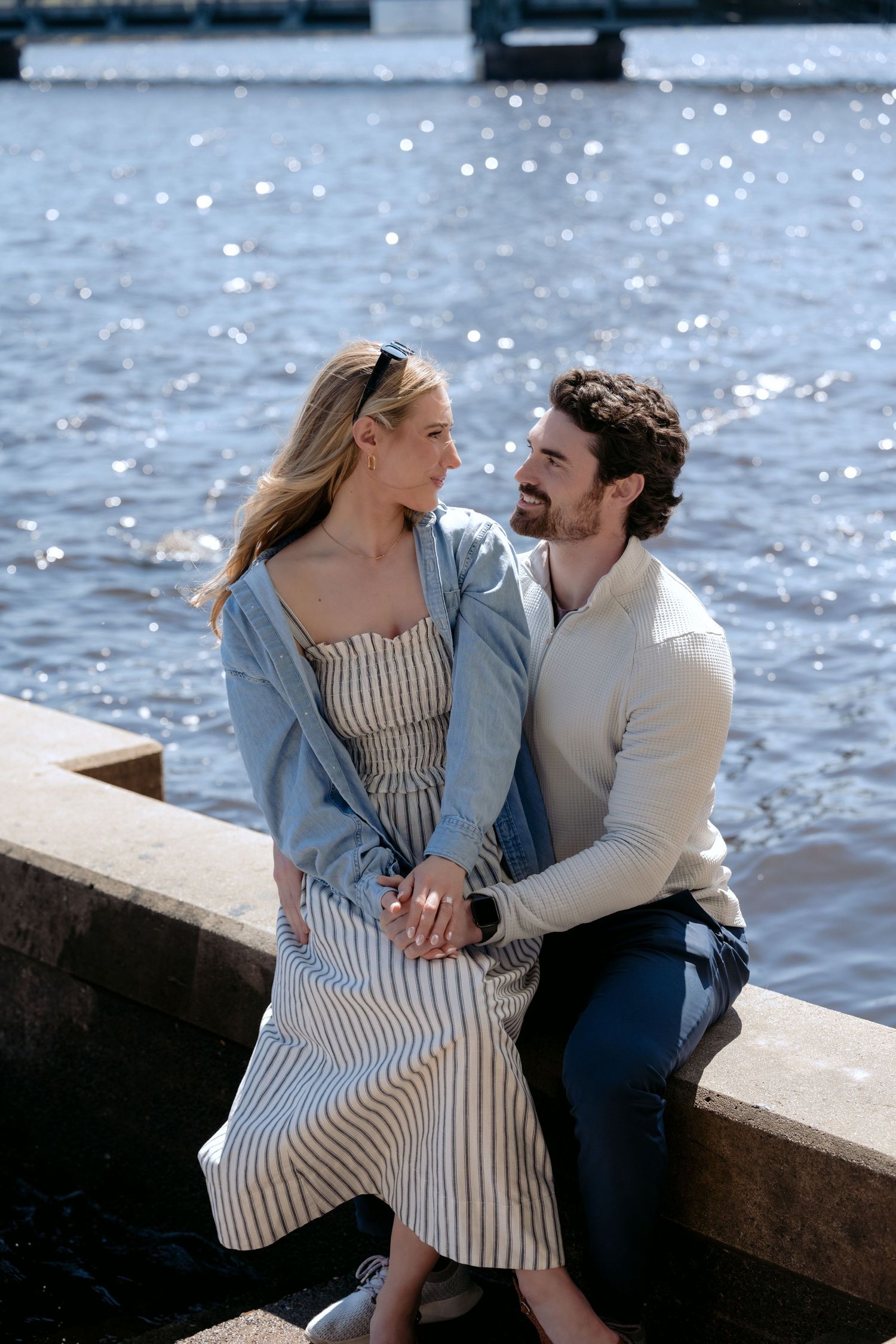 Couple sits near the St. Croix Rivers edge and enjoys a solitary moment together after their private proposal in downtown Stillwater, MN.
