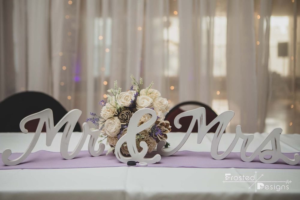 Mr. & Mrs. Wooden sign with flowers behind, at head table of wedding reception.