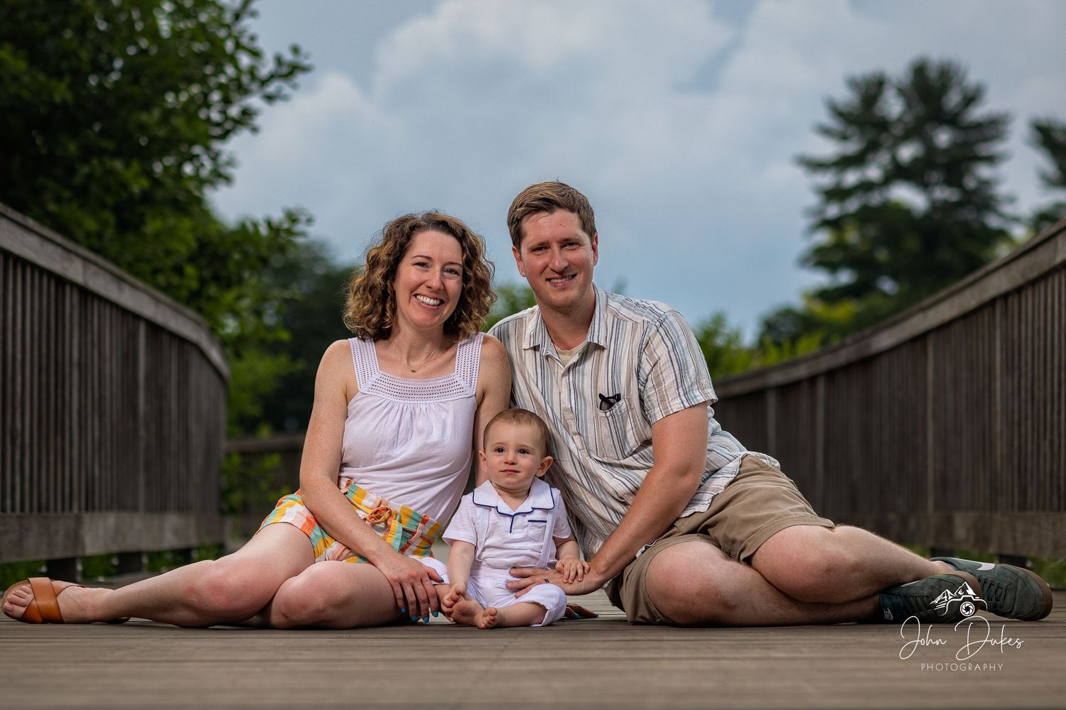 Family lying together on grass during an outdoor photo session.