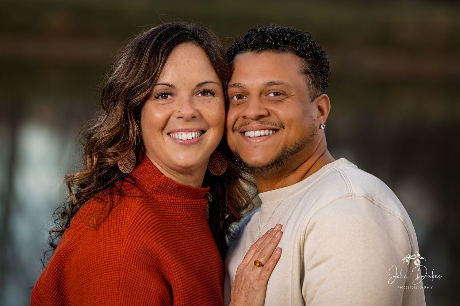 A couple wearing red and white poses for a casual outdoor portrait.
