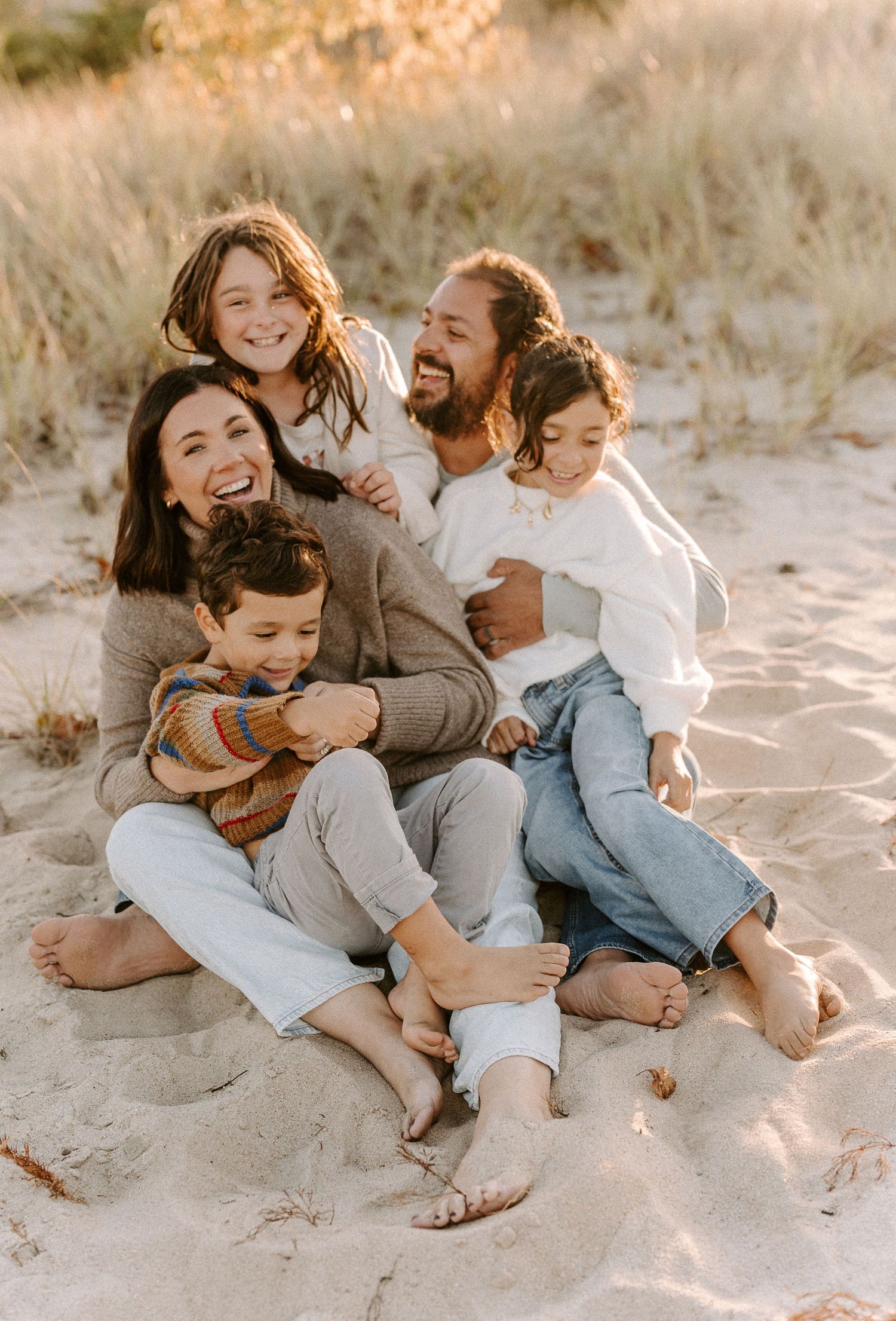 A family shares playful moments together on a sandy beach at sunset.