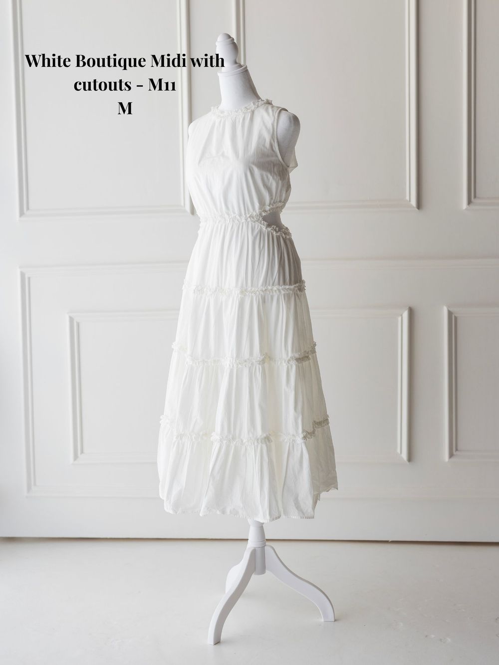 White cotton midi dress with cutout details and tiered skirt displayed from different views against white wall.