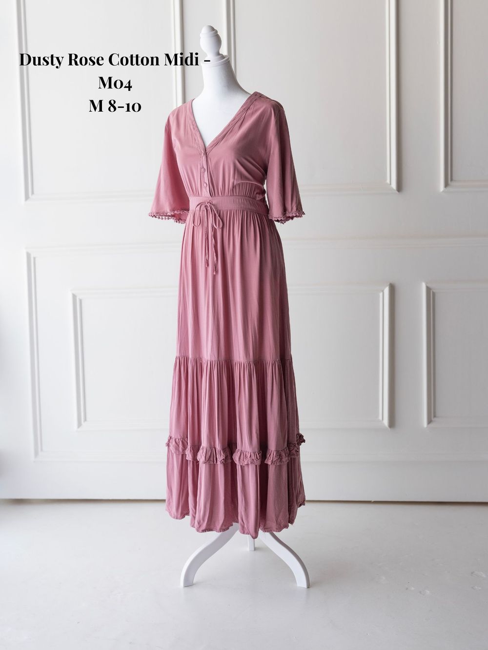 Dusty rose tiered midi dress with flutter sleeves and v-neckline displayed on white mannequin.