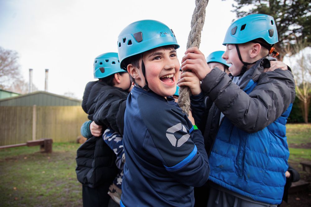 Group wearing blue climbing helmets participating in an outdoor team building activity.