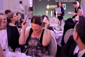 A guest in a purple dress reacts with laughter during an elegant dinner event.