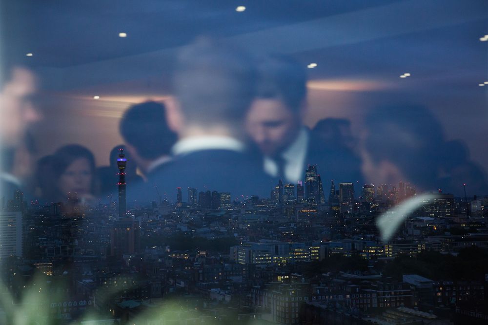 Blurred silhouettes against a cityscape backdrop with illuminated buildings and skyscrapers at dusk.