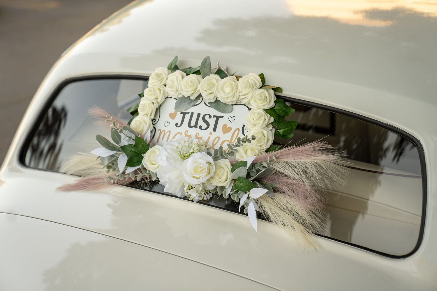 White rose 'Just' sign decoration on classic car rear window.