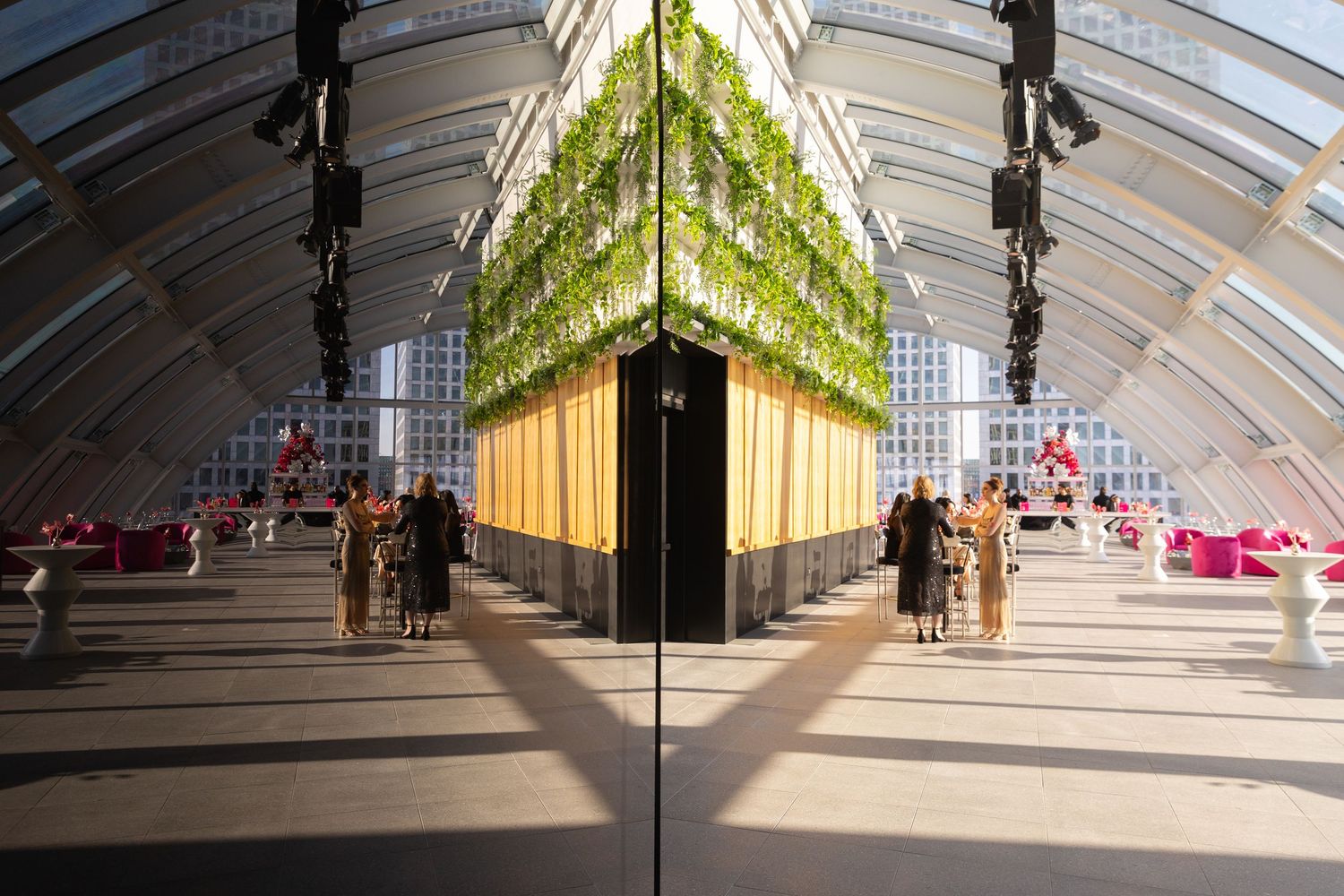 Modern art installation with hanging green glass elements in an arched gallery space with dramatic lighting and reflective floor.