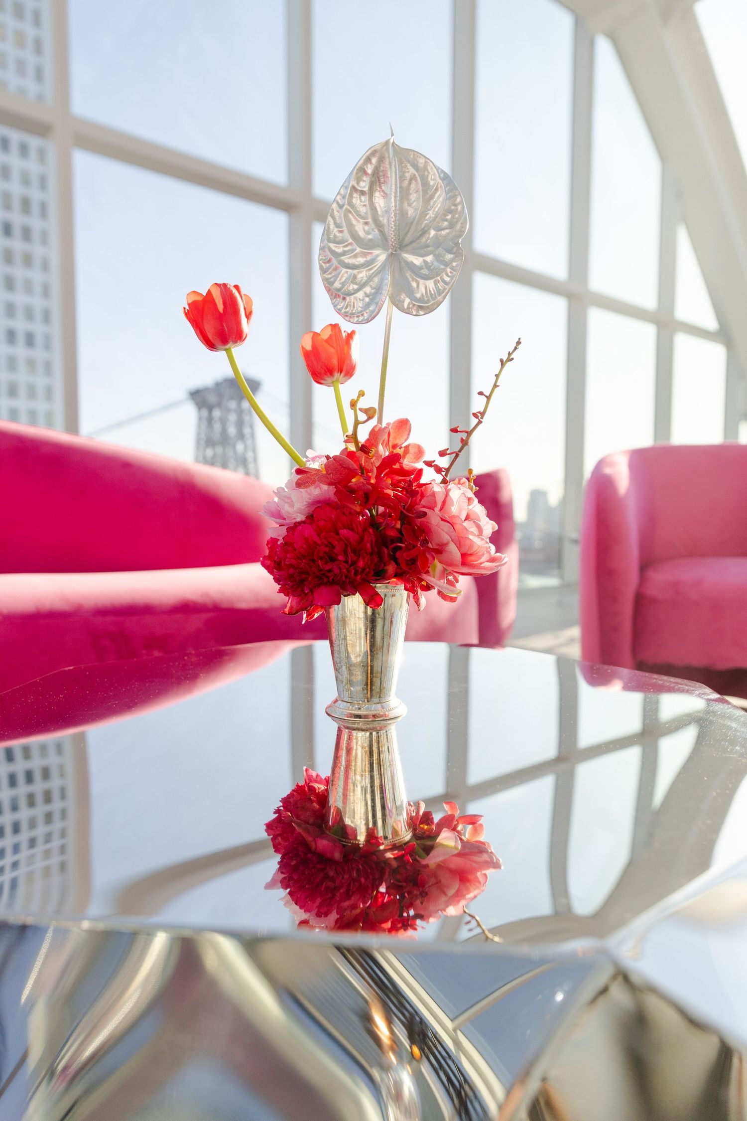 Red flowers in glass vases arranged on white windowsills with natural light streaming through.