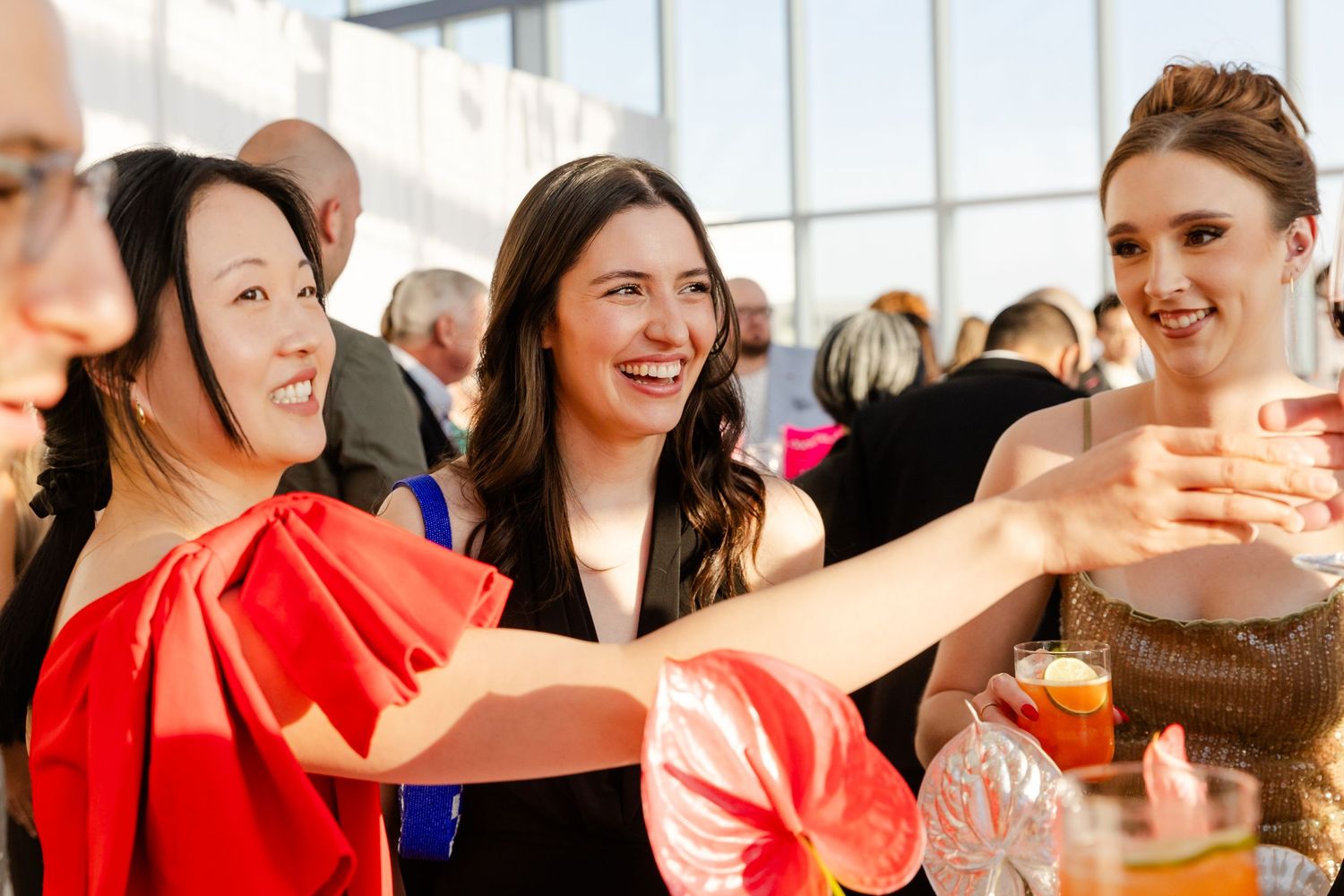 Group of partygoers in red attire celebrating and laughing together in a bright indoor space.
