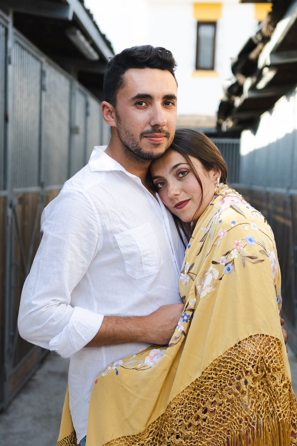 Romantic couple embraces in a hallway wearing white and yellow outfits with a crochet shawl.
