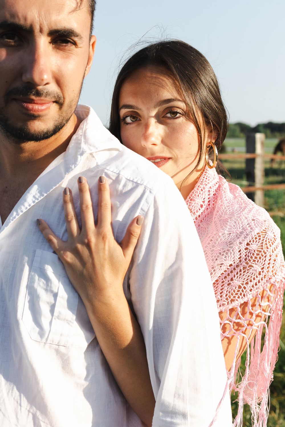 Intimate portrait series of a couple outdoors with woman wearing pink lace shawl and man in white shirt.