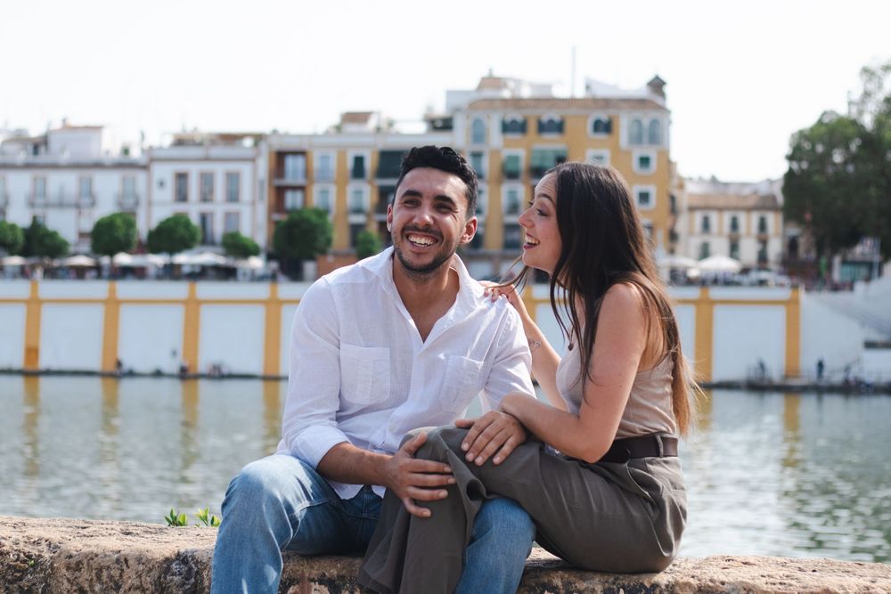 Couple enjoying a romantic moment together while sitting on a pier by the water at sunset.