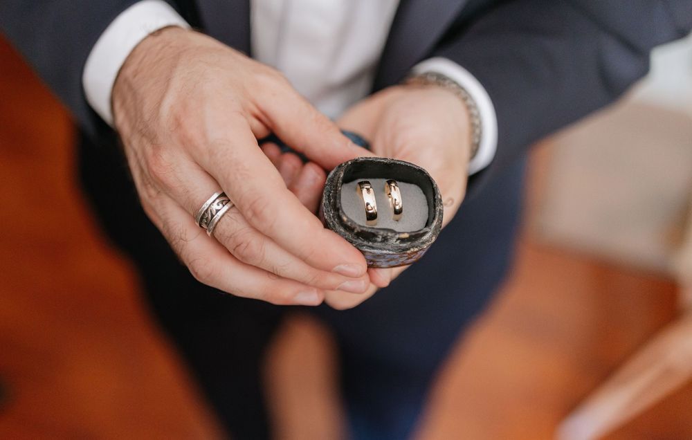Close-up view of hands exchanging wedding rings during an intimate ceremony.