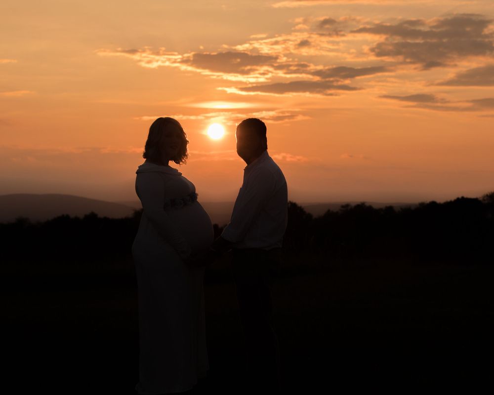 Silhouettes of a couple against a dramatic orange sunset sky.