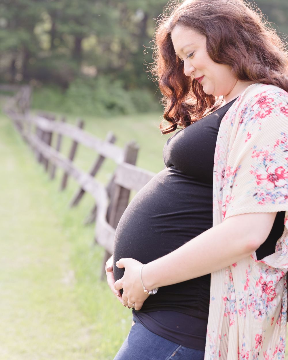 Intimate maternity photos taken in a grassy field with natural lighting.