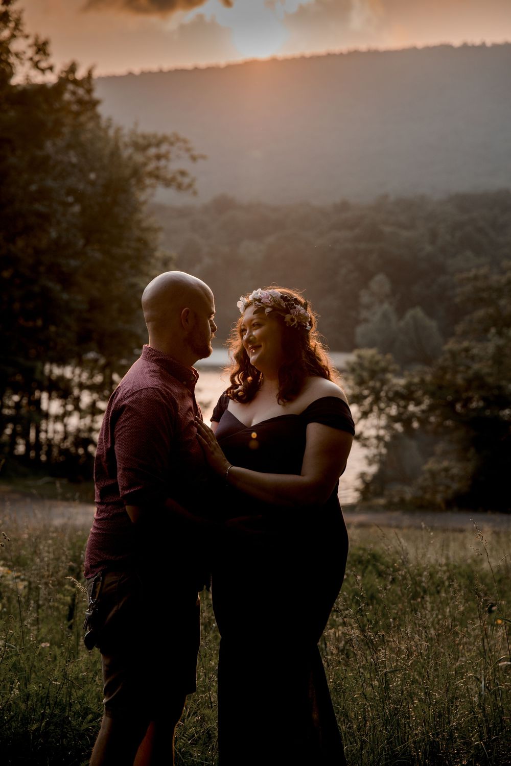 A romantic sunset maternity photoshoot in a scenic mountain field.