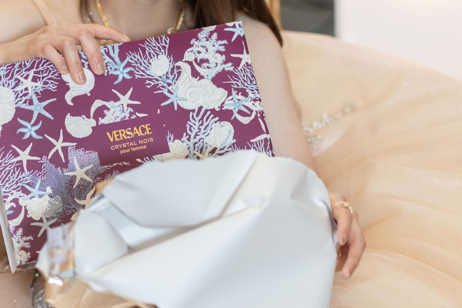A hand holds a Versace perfume box that a quince received as a gift for her birthday.
