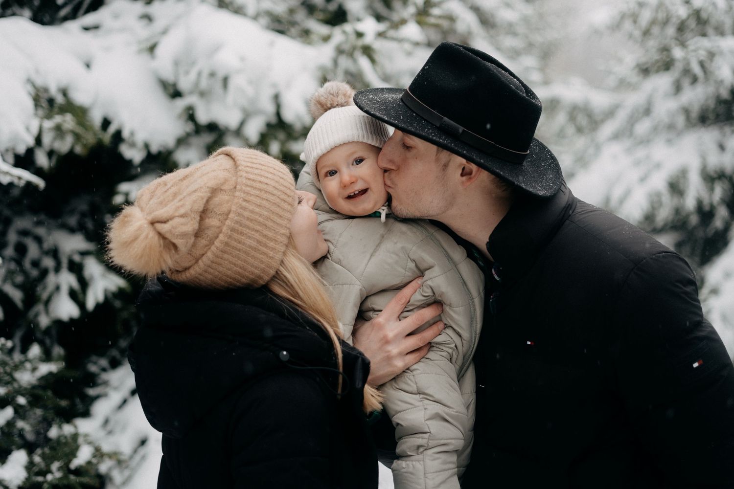 Intimate winter portrait of couple embracing in snowy forest setting.