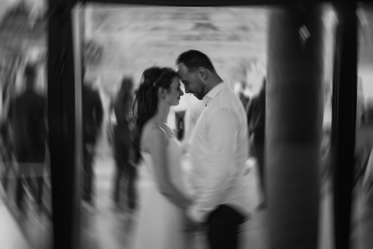Blurred black and white photo of couple in intimate moment at indoor event.