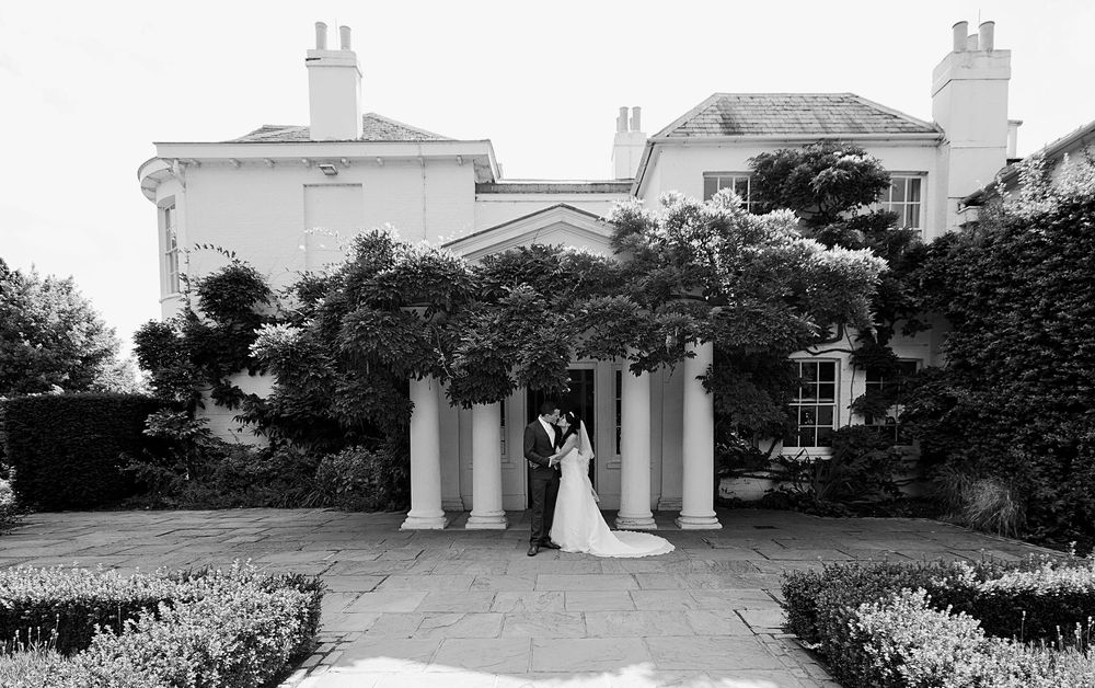 A panoramic black and white photo sequence showing the exterior of a stately mansion with columns and landscaped gardens.